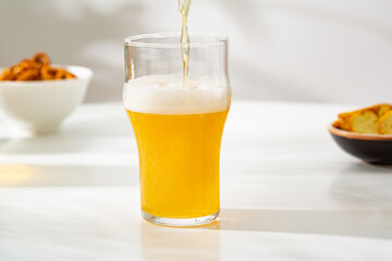 A glass light beer foam pouring and snacks in bowl food and drink