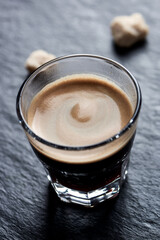 Coffee in glass cup on dark stone background. Close up.	