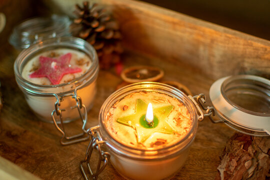 brennende Weihnachtskerze im Glas mit Stern sowie Sandelholz Spänen. Auf einem Tablett