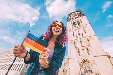 A young happy tourist or student girl with a German flag at the old town or Altstadt in Munster...