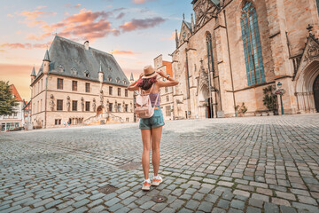 Happy woman tourist with backpack enjoying panorama of the city hall rathaus and market square of...