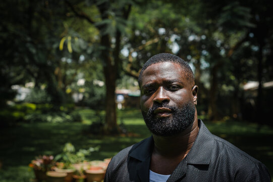 A black man in a garden posing for a portrait