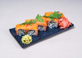 Portion of Philadelphia rolls on a beautiful rectangular plate. Pickled ginger and wasabi. Japanese cuisine. Sushi restaurant.