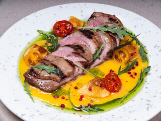 Grilled meat with delicious yellow sauce. Cherry tomatoes.  Beautiful plate. Fresh tasty food in restaurant.