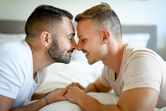 Two men couple in bed on a beautiful white bedroom