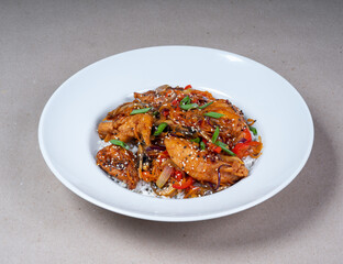 Asian cuisine. Close-up of white plate of rice and herb spicy fried chicken.