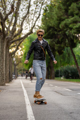 Fototapeta premium Adult woman with short hair and leather jacket learn to ride skateboard in a city. Urban lifestyle scene in Barcelona.