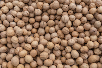 Textured surface of unpeeled (in shell) walnuts. Autumn agricultural fair.