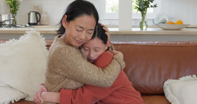 Love, hug and mother and daughter on sofa, spending time together in living room in Japan. Asian woman, child on couch in family home and happy relationship bonding with teenage girl on mothers day