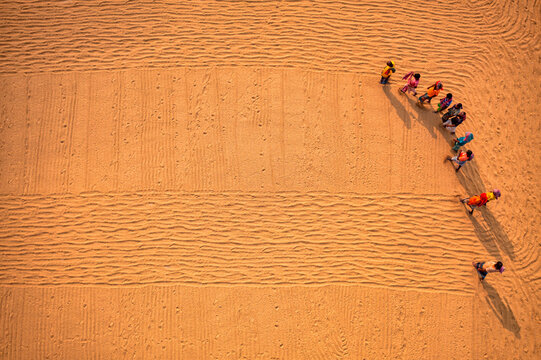 Aerial view of farmers working in a field drying rice on a rice field in Dhamrai, Dhaka, Bangladesh.