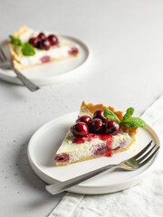Portion of cottage cheese casserole or pudding with cherry and mint leaveson white background. Cherry cheesecake