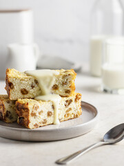 Portion of cottage cheese casserole or pudding with raisins poured with condensed milk on white table background