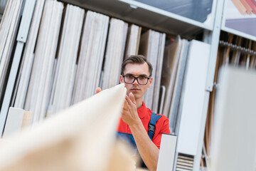 Fototapeta premium seller of the floor coverings store choosing the necessary samples of laminated boards .