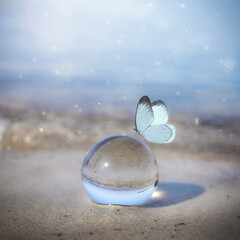 Glass lens ball on the beach reflecting the lake and sky. Concept of tranquility and zen. 