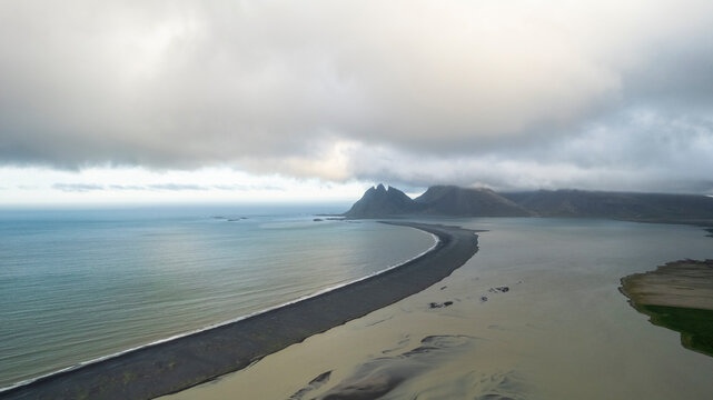 Aerial view of water formation at river estuary and Fjorur beach with mountain in background, Iceland.