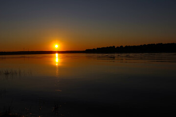 Naklejka premium Beautiful sunset reflected in the water on a huge lake