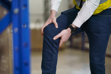Factory worker has injured or pain at knee joint. Injury from working not properly in working place, Concept insurance for people that on duty in warehouse industrial.