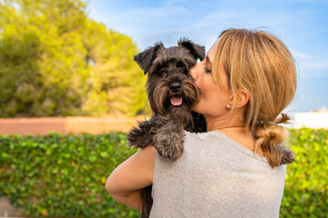 Beautiful woman hugging and kissing dog. Dog and owner together outdoors. Love and friendship between dog and owner