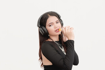 A Southeast Asian woman eating lollipop while listening to songs on her bluetooth headphones in a...