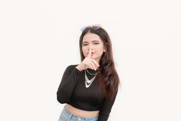 A young Asian lady does a quiet hand gesture implying not to tell a confidential information. Studio photo isolated in a plain white background.