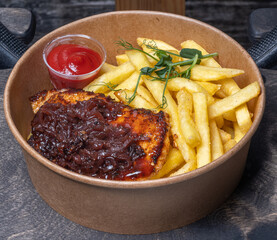 Close-up of tasty fried meat, fries and catchup in cardboard bowl. Take away food.