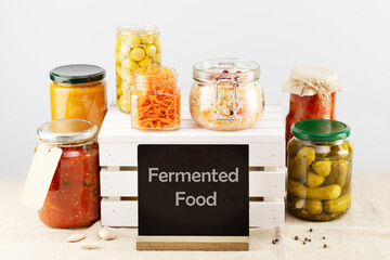 Seasonal pickled or fermented vegetables and mushrooms with chalk board with inscription Fermented Food on a light neutral background. Home food preserving or canning