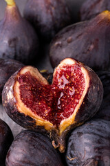 background with fresh and ripe figs, in the foreground an open fig forms a heart.
