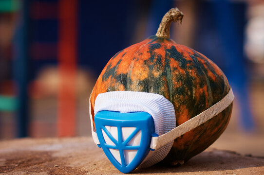 Spotted pumpkin in a respirator mask. Close up outdoor view of playground in blur. Selective focus
