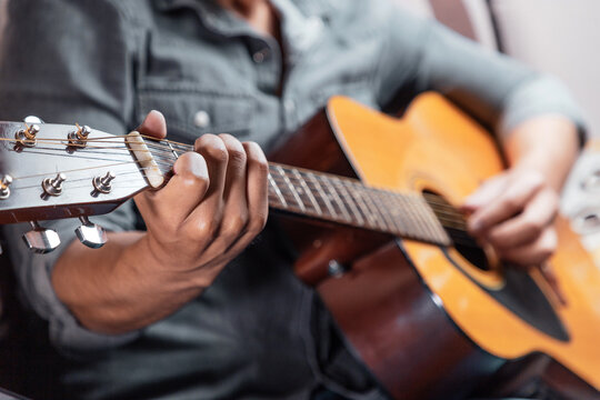 Hombre en casa con guitarra acústica, tocando y cantando. Concepto de músico compositor. guitarrista 