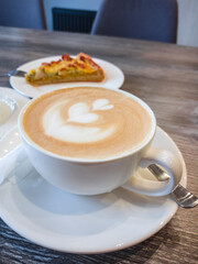 Delicious fragrant cappuccino with a pattern on the surface of the foam in a white porcelain cup