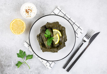 Dolma, sour cream, lemon, parsley on a gray background. Traditional Caucasian, Turkish, Armenian and Greek cuisine