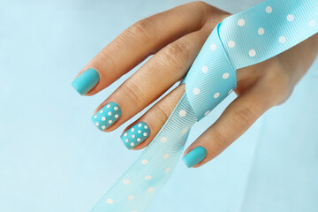 Manicure on short nails with blue nail polish with white dots.