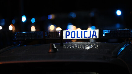 Akcja nocna  alarmowa policji - Sygnalizator błyskowy niebieski na dachu radiowozu policji polskiej w nocy. Światła policyjne.