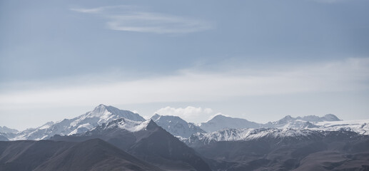 Panoramic view of mountain rock range, hills and peaks with snow and glaciers, monochrome landscape with cloudy sky