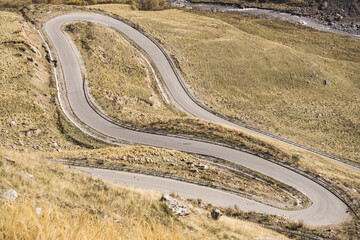 A winding mountain road serpentine down into the valley along the mountain slope, on a warm autumn day