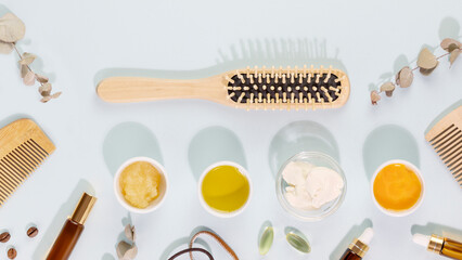 Hair care banner with wooden combs, ingredients for mask for hair, vitamins for health hair, natural oils and accessories on a blue background. Natural beauty products for hair