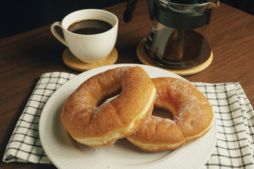 Freshly made donuts on the breakfast table with black coffee - 541787741