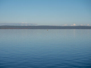 Calm blue water of Onega Lake in Karelia in northwestern Russia on a clear, windless, sunny autumn day