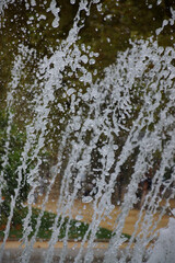 Wasserfontänen spritzen aus Düsen an einem Springbrunnen. Kurzzeitaufnahme. Viele Tropfen scheinen still und schwerelos in der Luft zu stehen. 