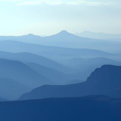 Mountain range landscape with blue silhouetted mountains on a misty, foggy morning