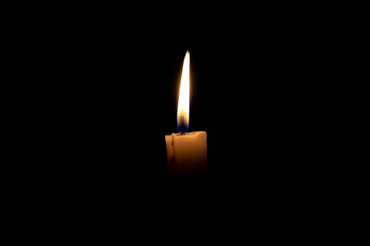 Burning candle. The candle burns in the dark. Candle flame on a black background