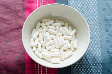 White capsule pill in bowl on tablecloth