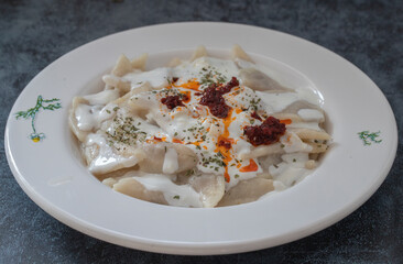 Turkish traditional food ravioli with yoghurt and tomato sauce in plate, manti