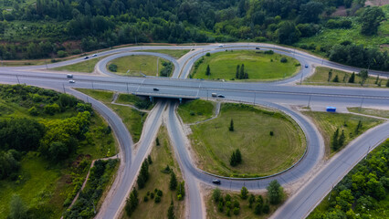 Car interchange on the highway, on a sunny summer day. View from the drone, from above. Suburban park area.
