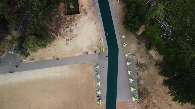 Athletes are running long distance during triathlon held in Russia. Sportsmen are taking part in race filmed from above by drone. People are jogging on special rode in park.