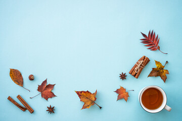 Autumn flat lay background on blue. Hot tea, fall leaves and spices. Flat lay with copy space.