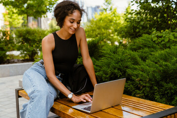 Young beautiful smiling curly woman working with laptop