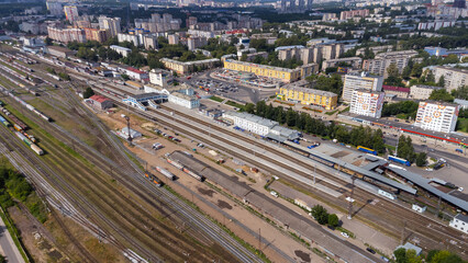 Fototapeta premium City, locality. Railway station. Passenger and cargo transportation. Residential area on a sunny summer day. Apartment buildings, high-rise buildings. The view from the drone, from above.