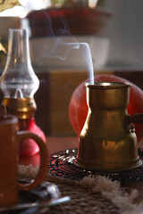 Yellow metal vintage cerve with steam over it with pumpkin and red lamp on wooden table, cozy autumn morning concept.