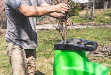 Man putting tree branches into garden shredder